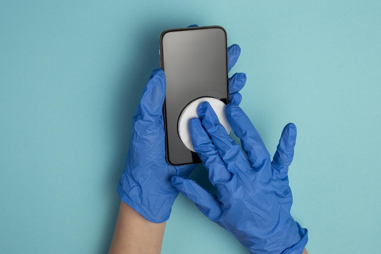Hands medical gloves wipe smartphone screen with disinfectant cloth close up hands are cleaning mobile phone isolated blue background smartphone disinfection 360281 1318
